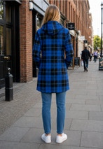 Woman in a blue and black plaid hoodie dress, back view on a city street