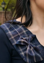 Close-up of a navy tartan bow rosette sash on the shoulder with fringed ends