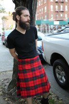 Robertson red tartan kilt, side view on a city street beside a tree