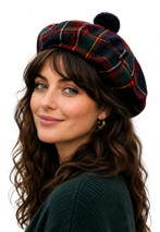 Woman wearing a tartan tam in dark green, red and navy with a pom-pom, front view