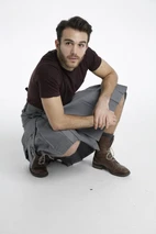 Man crouching in grey slash pocket kilt, showing pleats and brown boots
