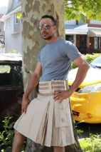 Beige street style utility kilt with striped belt and cargo pocket, outdoor front view