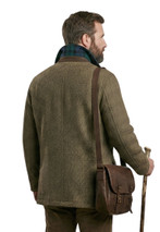 Back view of man in olive tweed chore coat with leather satchel and walking stick