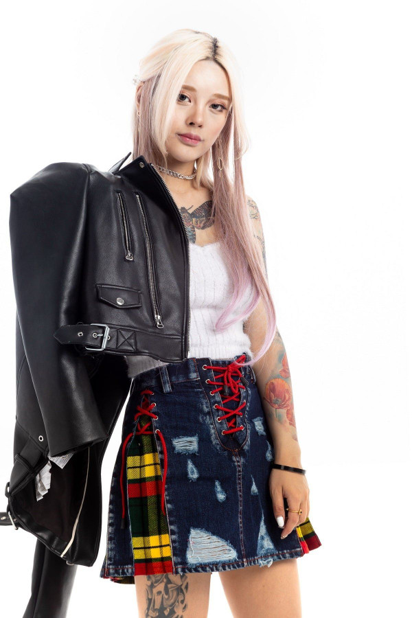 Woman in ripped denim mini skirt with red lace-up front and yellow tartan side panel