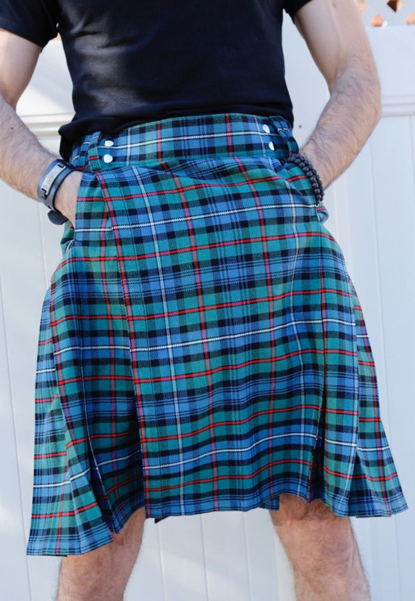 Close-up of blue and green tartan kilt with red lines worn with hands in pockets