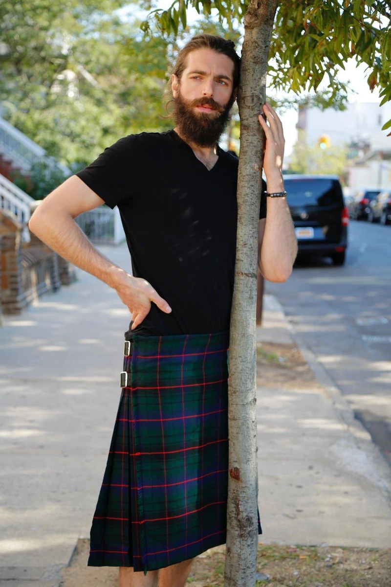 Man leaning on tree in green and navy Davidson tartan kilt with red lines