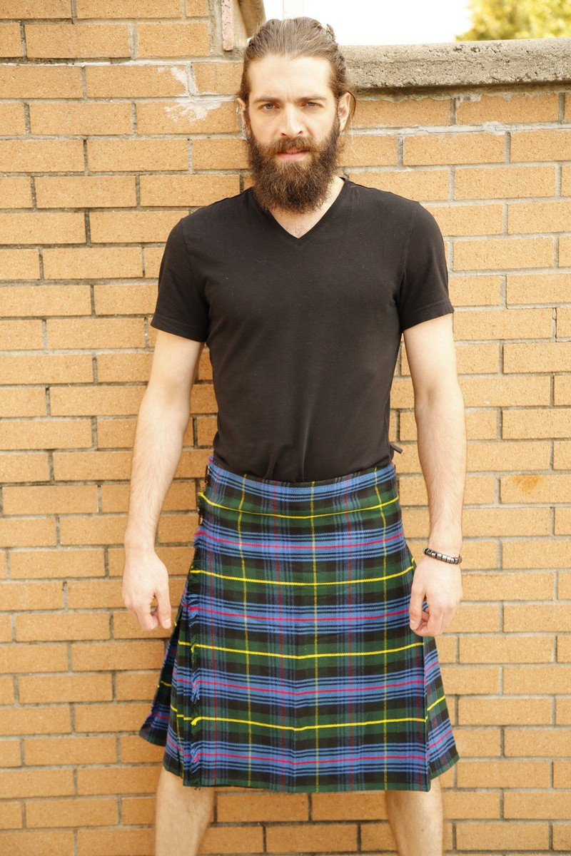 Man in Farquharson tartan kilt standing against a brick wall, front view