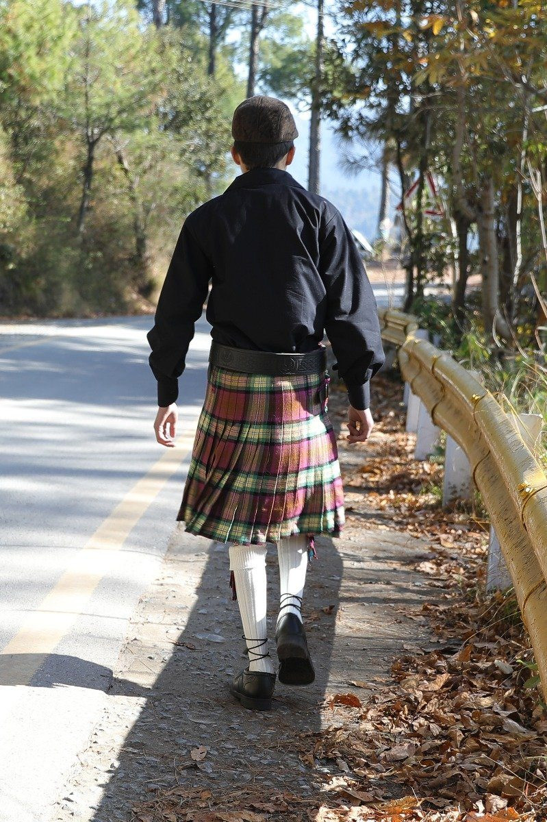 Back view of Isle of Skye bespoke kilt worn walking along a tree-lined road