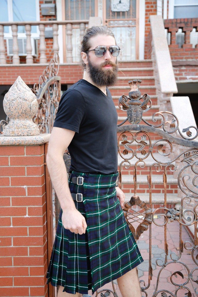 Man in Lamont bespoke kilt in navy and green tartan by an iron gate