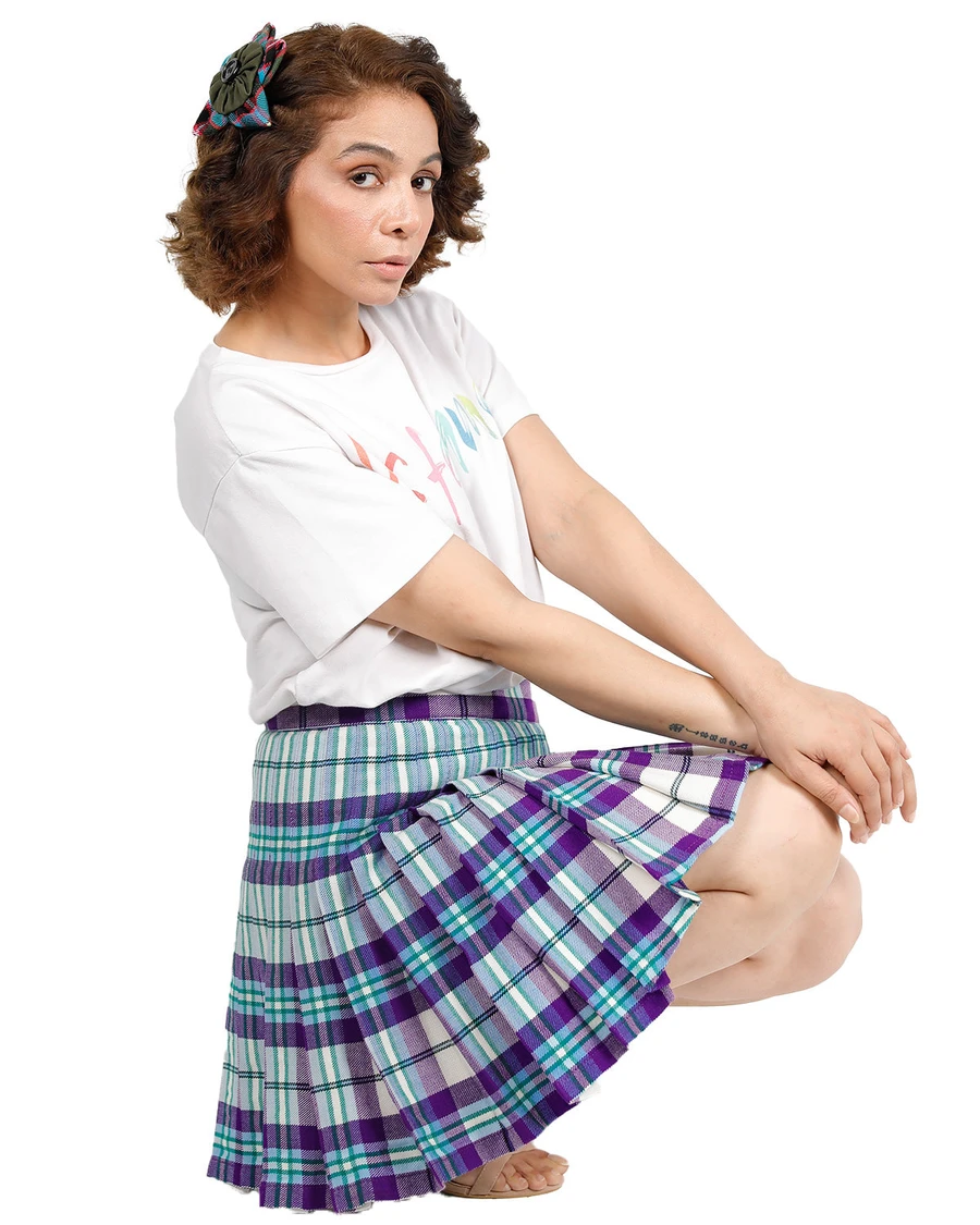 Woman crouching in purple, teal and white tartan wrap skirt with knife pleats