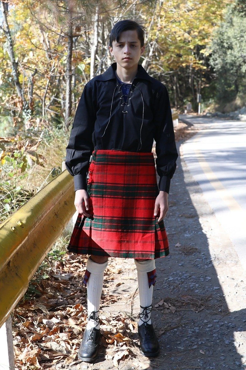 Teen boy in Maxwell tartan kilt with black jacobite shirt on a woodland road