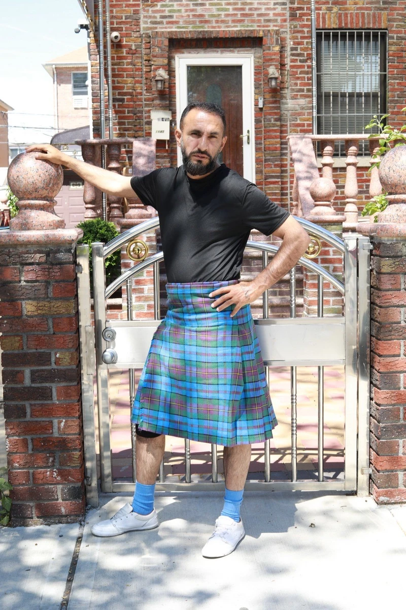 Man in Orkney tartan kilt leaning an arm on a brick gate post