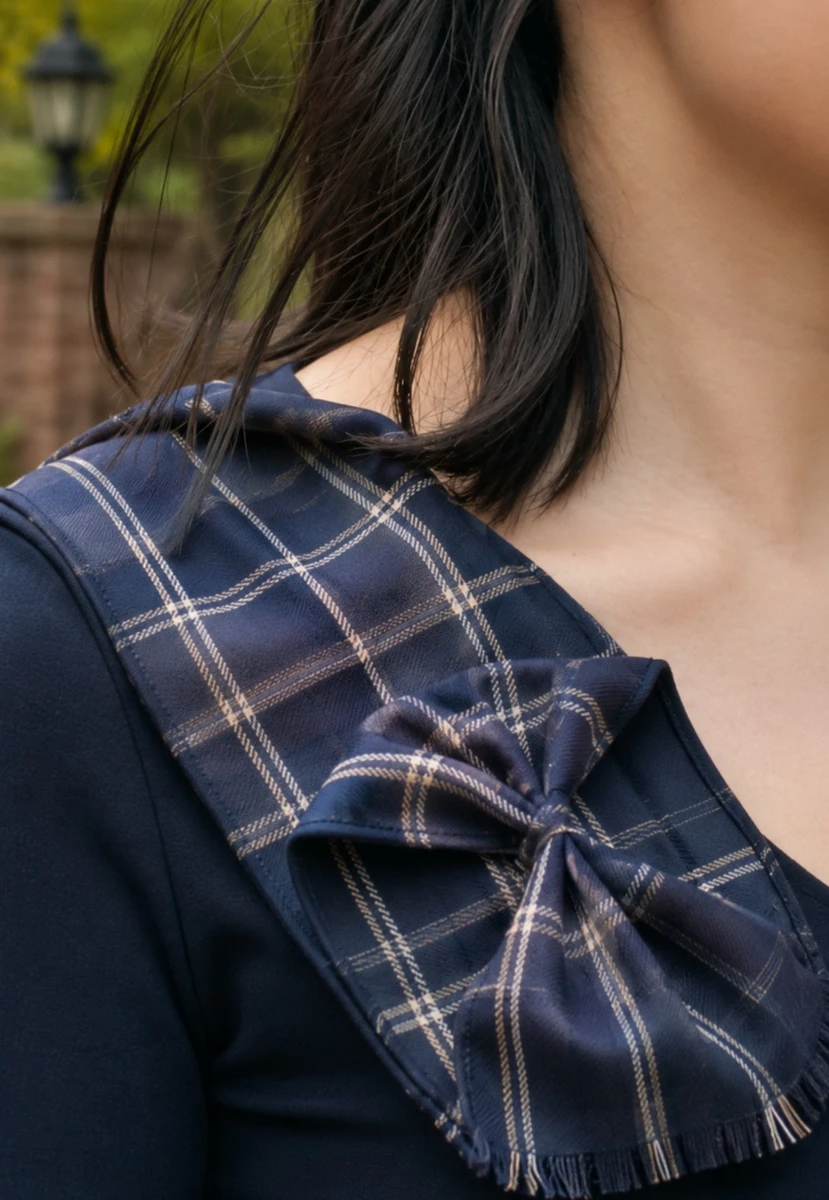 Close-up of a navy tartan bow rosette sash on the shoulder with fringed ends