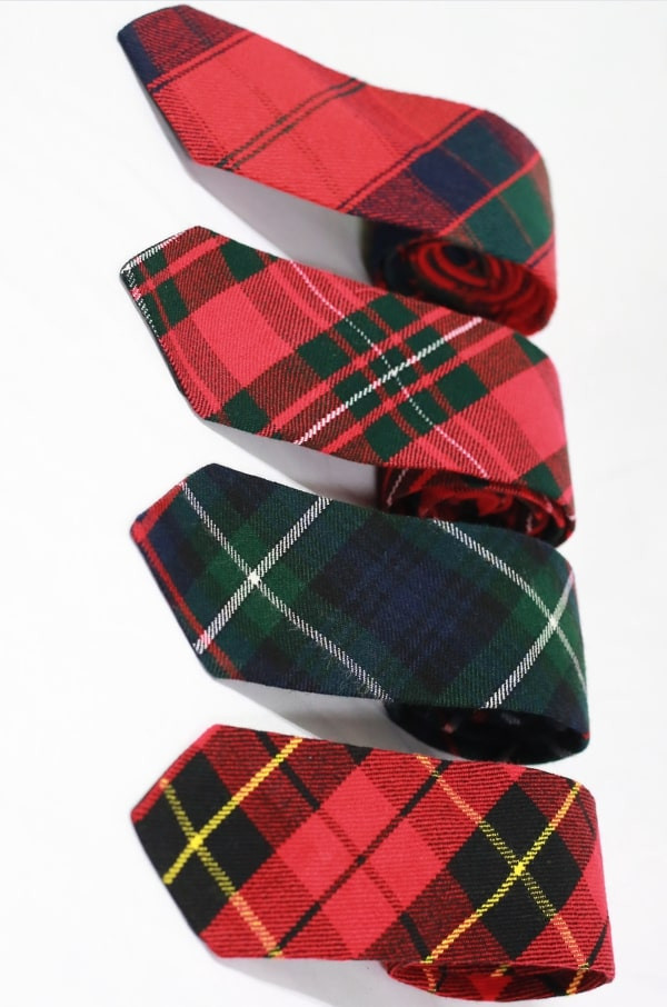 Four narrow tartan ties in red and green tartans arranged in a row