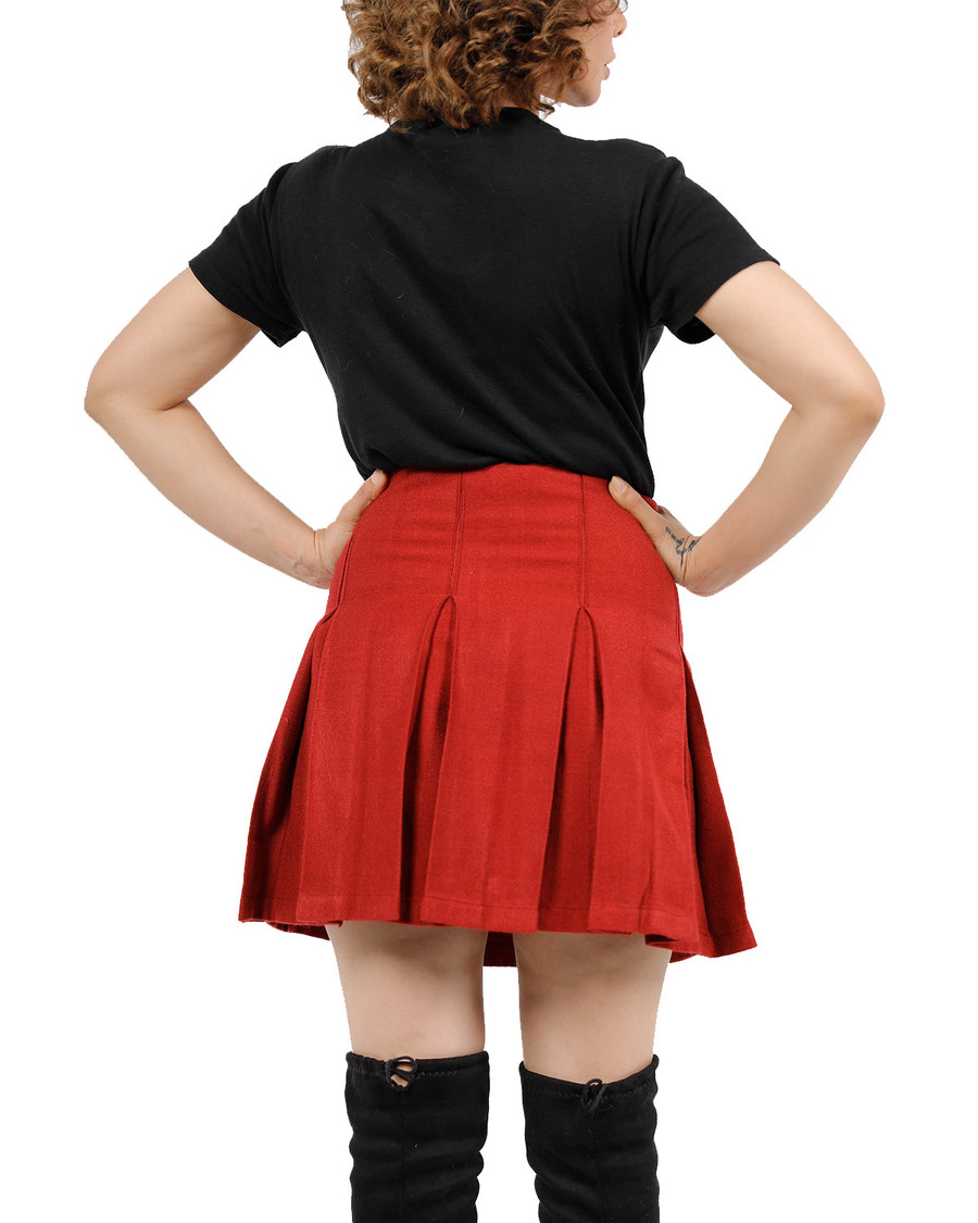 Back view of red pleated twirl skirt worn with black top and boots