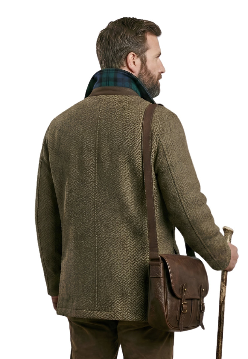 Back view of man in olive tweed chore coat with leather satchel and walking stick