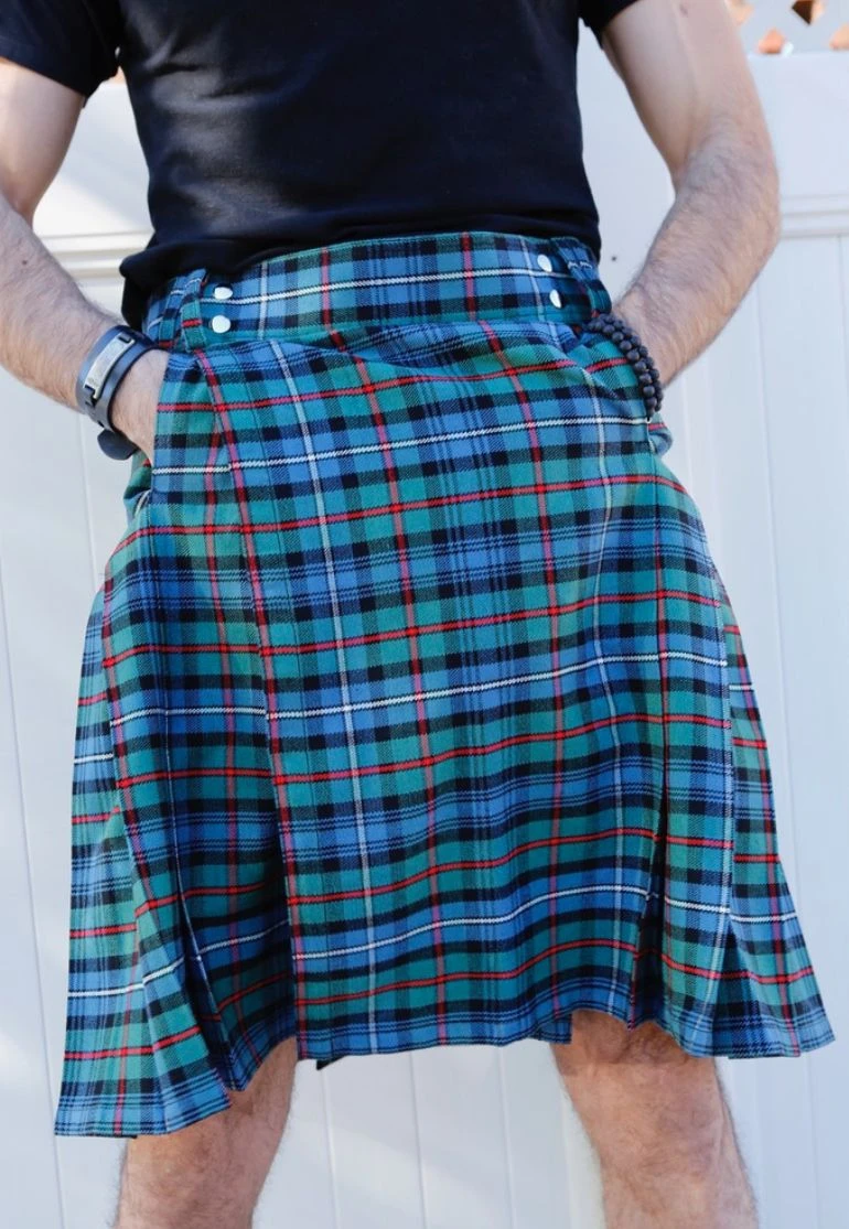Close-up of blue and green tartan kilt with red lines worn with hands in pockets
