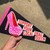 A hand holding a black pennant with red, white, and hot pink to show size.  Pennant says Support Your Local Drag Queen with a large bedazzled high heel shoe illustration.