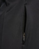 A close-up of a black softshell jacket featuring a zippered pocket. The fabric appears smooth and durable.