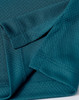 A close-up of a teal fabric featuring a jacquard knit pattern, showing the texture and stitching details.