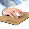 A hand using a white mouse on a cork-coloured mouse mat featuring a logo.