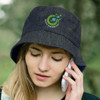 A denim bucket hat with a logo, worn by a person speaking on a phone. The hat is dark blue.