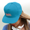 A turquoise flat peak cap with an embroidered logo, worn by a person with long hair.