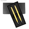 A black rectangular box containing two gold pens, nestled in black foam padding, with a logo on the box.
