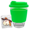 A reusable coffee cup with a bright green silicone lid and sleeve, accompanied by a packet of jelly party mix sweets.
