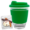 A reusable coffee cup with a clear glass body and a green silicone lid and sleeve, accompanied by a pack of jelly lollies.