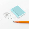 A light blue book-shaped rubber eraser beside pencil marks and a sharpened orange pencil on a white surface.