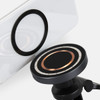 A close-up of a black wireless car charger with a copper ring, positioned near a smartphone's charging pad.