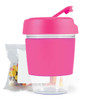 A pink reusable coffee cup with a clear base and a lid, accompanied by a bag of colorful jelly beans.