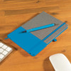 A gray notebook with a blue cover and a matching blue pen, resting on a wooden desk beside a keyboard and mouse.