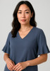 A fluted sleeve blouse in slate blue, featuring a V-neckline and a relaxed fit. The image has a branding logo.