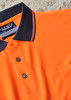 An orange short sleeve polo shirt with a black collar and buttons, featuring a pocket on the front.