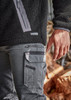 A close-up of men's grey work pants featuring multiple pockets and a zipped side pocket, paired with a black fleece top.