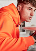 An orange unisex water-resistant hoodie with a logo, featuring a male model.