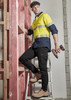 Mens lightweight outdoor pant in black, paired with safety boots, on a ladder in a construction setting. Features a logo.