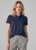 A woman wearing a navy short sleeve polo shirt, paired with light grey sweatpants, with a logo on the shirt.