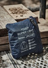 A navy blue packable rain jacket neatly folded and zipped, featuring a logo and information on the packaging.
