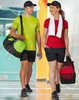 A sports travel bag in black with green and red accents, alongside two individuals in activewear and caps.