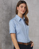 A blue women's short sleeve button-up shirt with a collar, featuring a logo on the chest and a belt.