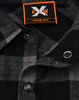 A black and grey plaid unisex flannel button-up shirt featuring snap buttons and a logo tag.