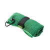 A green travel towel, rolled up with a black strap and carabiner for attachment. It has a textured surface.