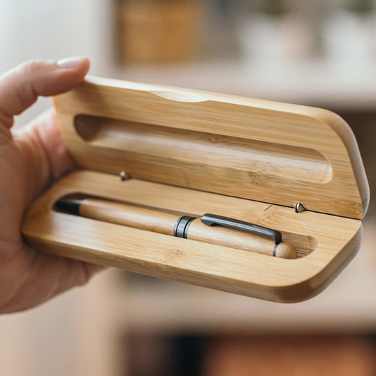 A bamboo case holding a natural wood pen with a silver clip, featuring a smooth, minimalist design.