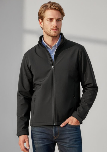 A man wearing a black soft shell jacket, standing against a neutral background, featuring a logo on the jacket.