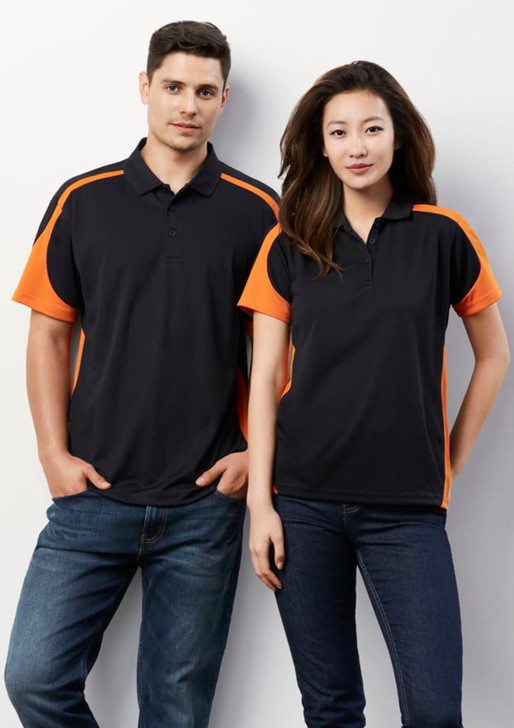 A black polo shirt with orange accents, featuring a logo, modelled by a man and a woman against a white background.