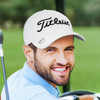 A light-coloured cap with a logo, worn by a smiling man on a golf course.