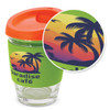 A drink bottle featuring a clear glass body, orange lid, and green silicone sleeve with a tropical palm design.